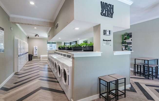 on-site laundry room in fusion Fort Worth apartments with herringbone flooring and large waiting area