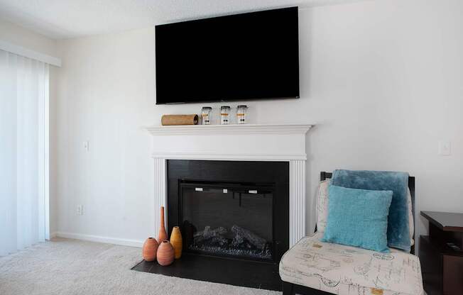 A living room with a fireplace, a sofa and a television mounted above it.