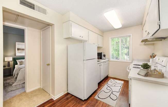 A small white kitchen with a refrigerator, sink, and cabinets.