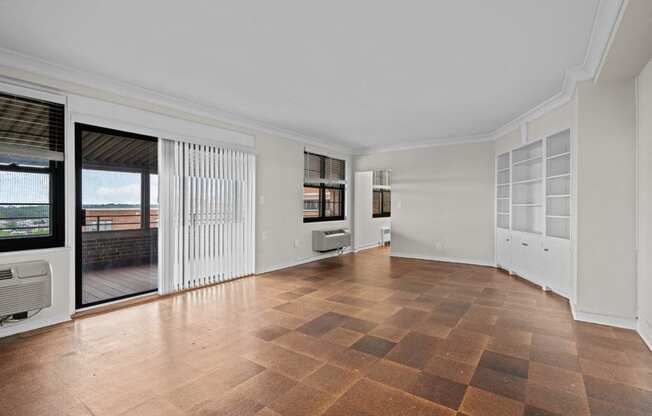 an empty living room with a sliding glass door to a balcony