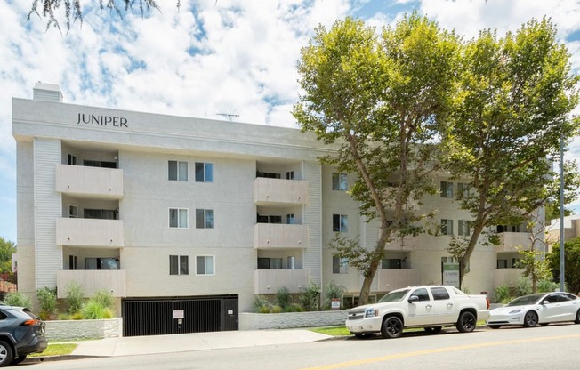 a white apartment building with cars parked in front of it