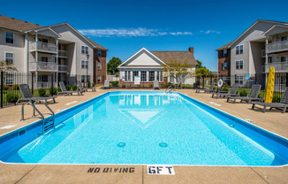 our apartments have a swimming pool with chairs and an apartment building