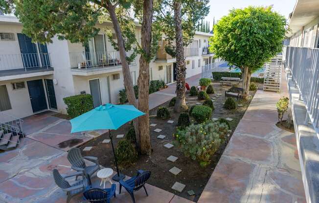 a courtyard with a blue umbrella and tables and chairs