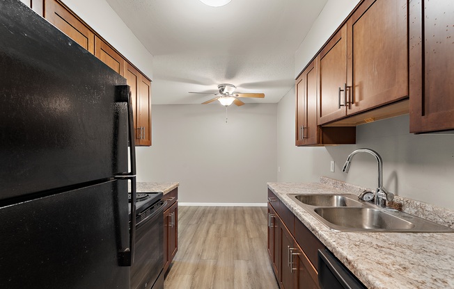 A kitchen with a black refrigerator and wooden cabinets.