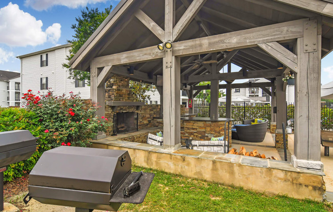 a backyard with a grill and a patio with a fireplace at Avalon Apartment Homes, Starkville, 39759