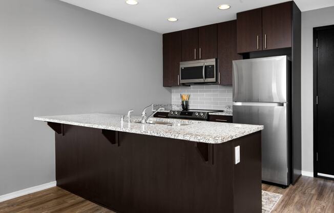 a kitchen with a granite counter top and a stainless steel refrigerator