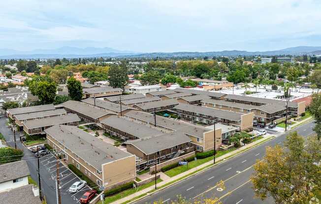 A view of a residential area with apartment buildings and cars parked on the street.
