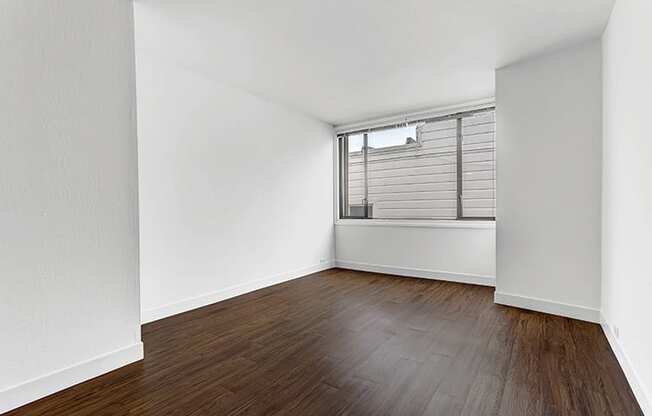 a bedroom with hardwood floors and a large window