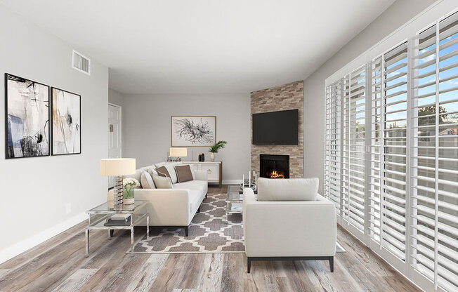 Hardwood floored living room with stone accented fireplace and large exterior windows.