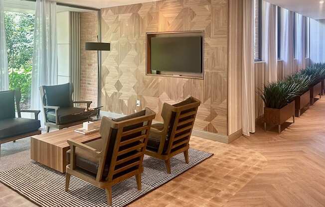 A living room with a television, chairs, and a rug.