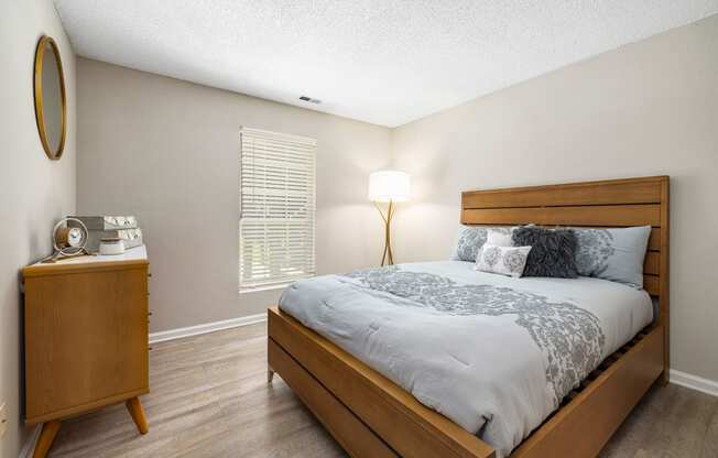 a bedroom with a bed and a dresser with a lamp at View at Lake Lynn, North Carolina, 27613