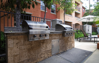 A wall of outdoor grills is in front of a building.