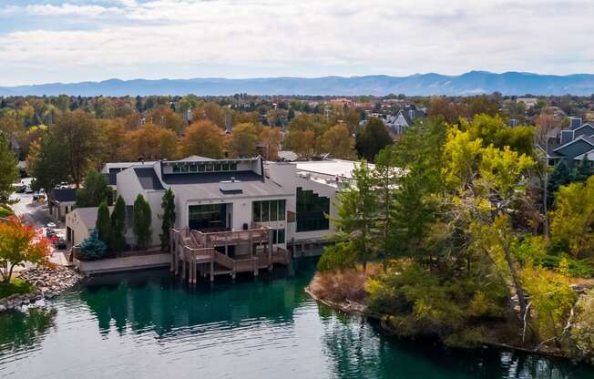 an aerial view of a house on a lake with mountains in the background at Ashford Belmar Apartments, Lakewood, CO 80226