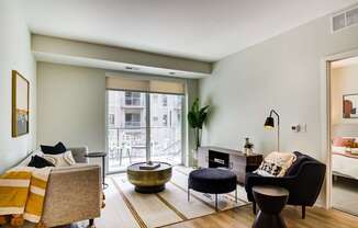 A living room with a grey couch, a black chair, and a yellow throw blanket.
