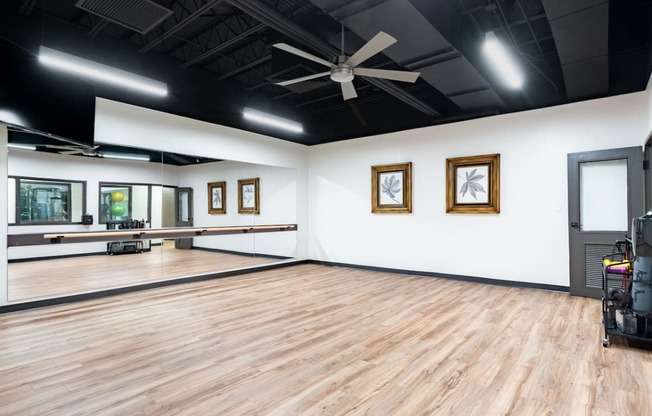 an empty dance studio with a hardwood floor and white walls