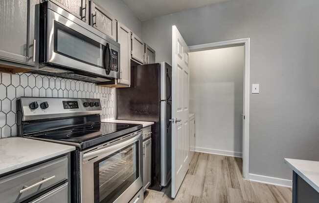 A kitchen with a white tile backsplash and stainless steel appliances.