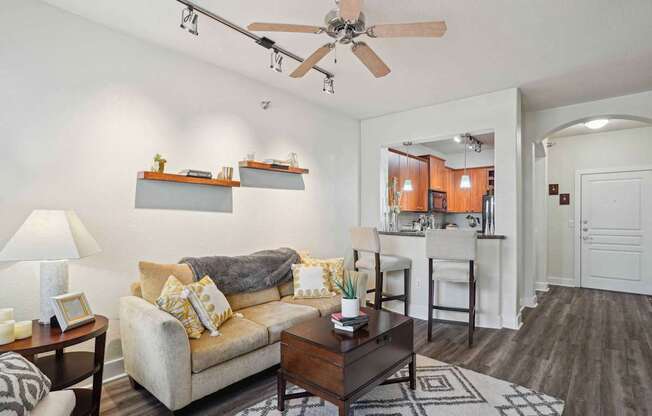 A living room with a couch, a coffee table, and a ceiling fan.