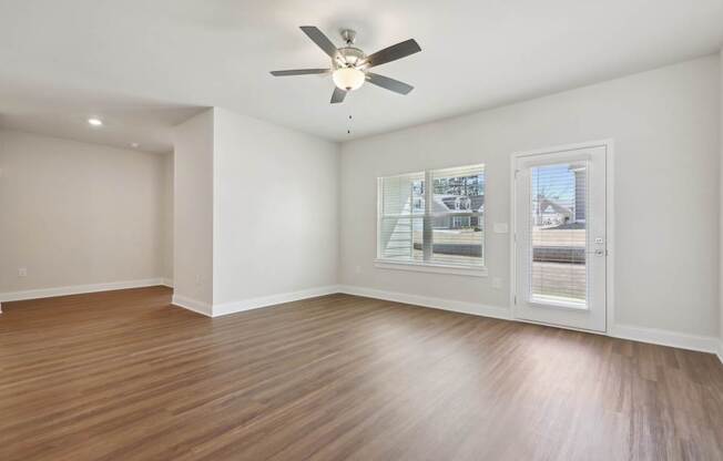 A room with a ceiling fan and a window overlooking a street.