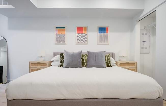 a bedroom with a large bed and three paintings on the wall