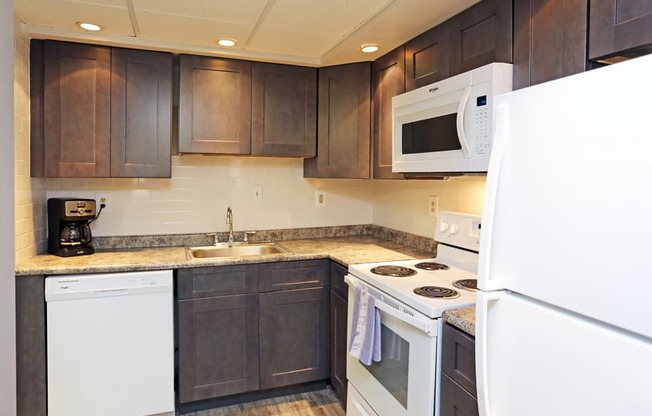 a kitchen with white appliances and dark wood cabinets