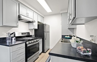 a kitchen with stainless steel appliances and black counter tops and white cabinets