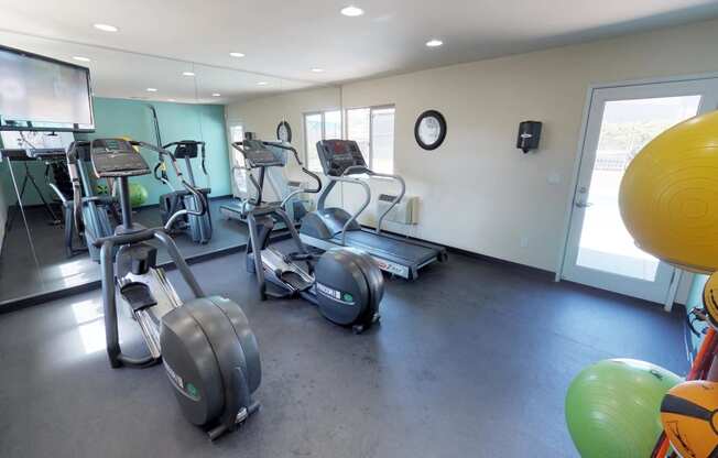 Stationary bikes, treadmill reflected in mirrored wall of fitness center