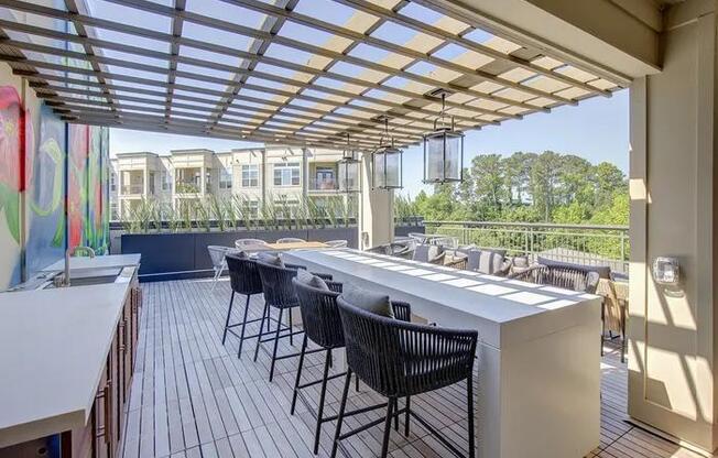 A patio with a white counter and black chairs.