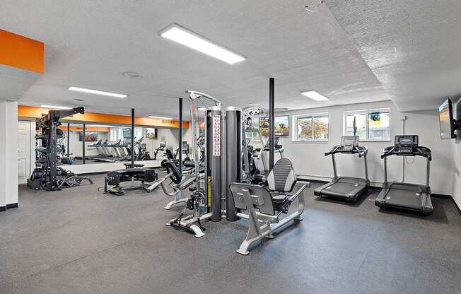 A gym with a variety of equipment including treadmills, weights, and exercise machines.