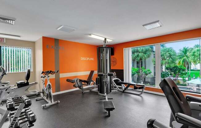 A gym with orange walls and a variety of equipment.