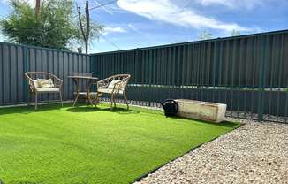 a yard with grass and chairs and a fence
