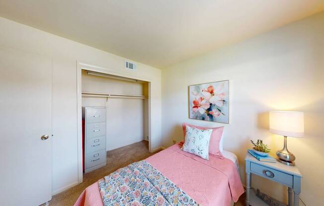 A bedroom with a pink bedspread and a bed with a floral pattern.