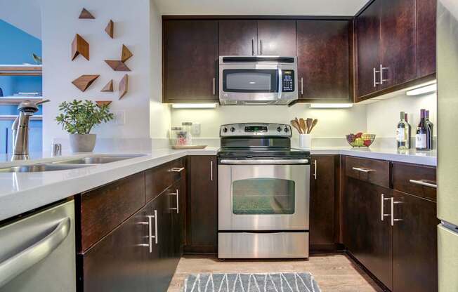 A modern kitchen with dark wood cabinets and stainless steel appliances.