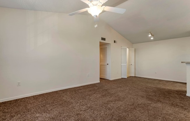 the spacious living room with carpeting and a ceiling fan