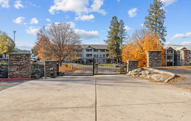 the gate at the conclusion of a driveway with an apartment building in the background