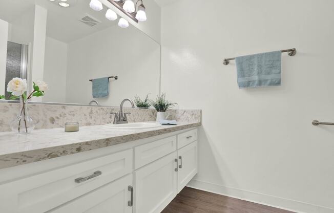 a white bathroom with a sink and a mirror at Willow Tree Apartments, Torrance, CA