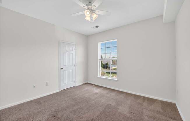 A classic 2 style bedroom with a ceiling fan and a window showing a view of a street.