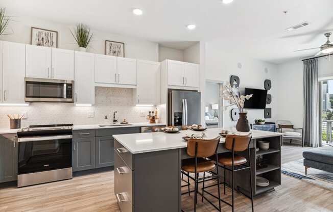 an open kitchen and dining area with stainless steel appliances and white cabinets