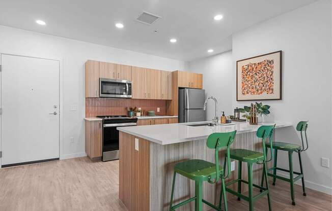 A kitchen with a white counter top and green chairs.