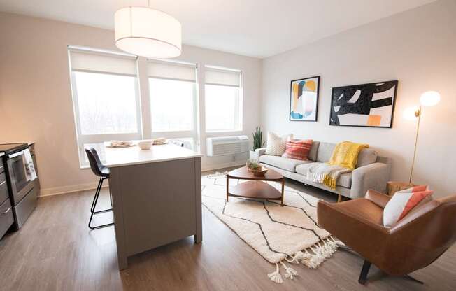 A modern living room with a grey sofa, a wooden chair, and a coffee table.