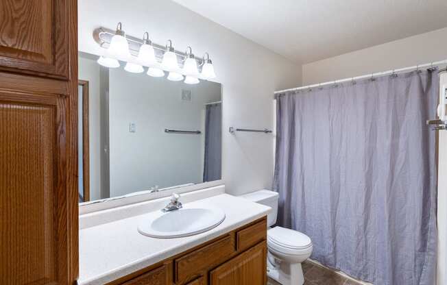 a bathroom with a shower toilet and sink and a mirror. Fargo, ND Oxford Apartments