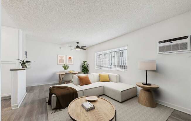 A living room with a white couch, a wooden coffee table, and a ceiling fan.