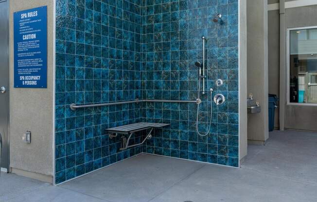 a blue tiled shower stall in a public restroom at Loma Villas Apartments, California, 92408