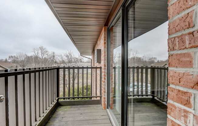 a balcony with a wooden deck and a brick wall