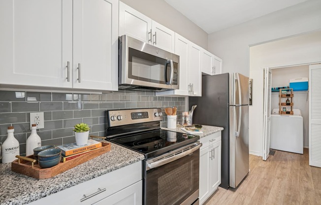 A kitchen with white cabinets and a black refrigerator.