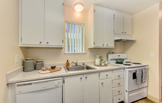Kitchen with white cabinets and appliances, including dishwasher and stove/oven. at Renaissance Park Apartments, Davis ,36305