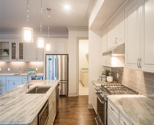 A bright kitchen with hardwood floors, white cabinetry, and stainless steel appliances.