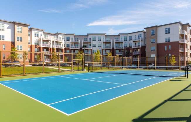 a tennis court with apartments in the background