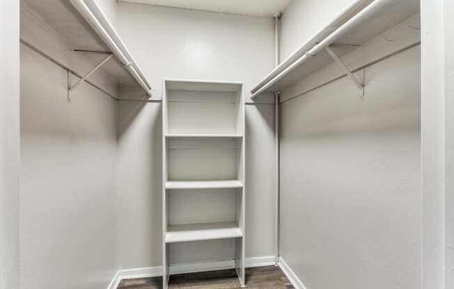 the walk in closet of a studio apartment with empty shelves