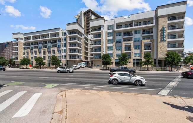 an empty street with cars parked in front of an apartment building