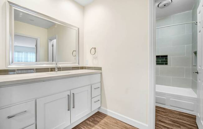 a bathroom with white cabinets and a large mirror and a shower